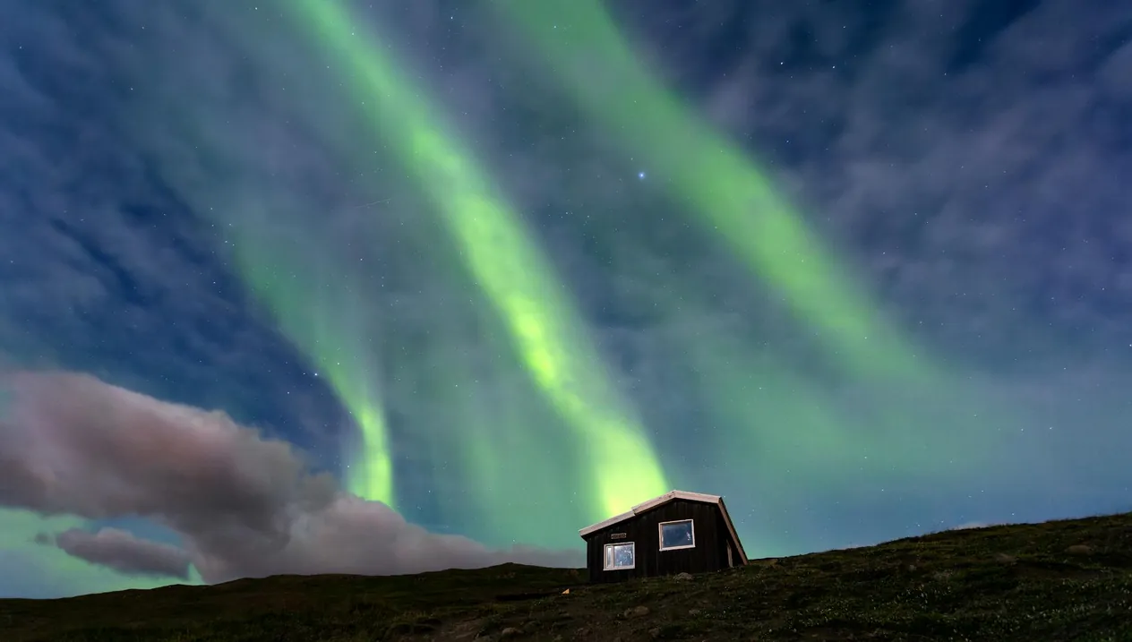 Northern Lights in the sky over a rustic cabin in Akureyri