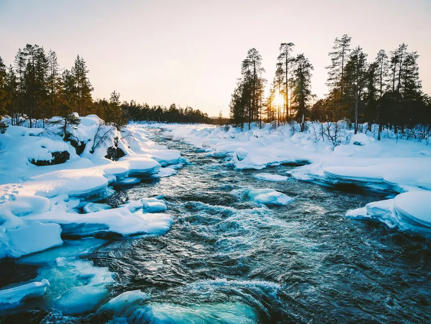 The Juutuan river at Inari in Finland isn’t frozen even in winter. The sun ist going down and it’s rather early about 3pm