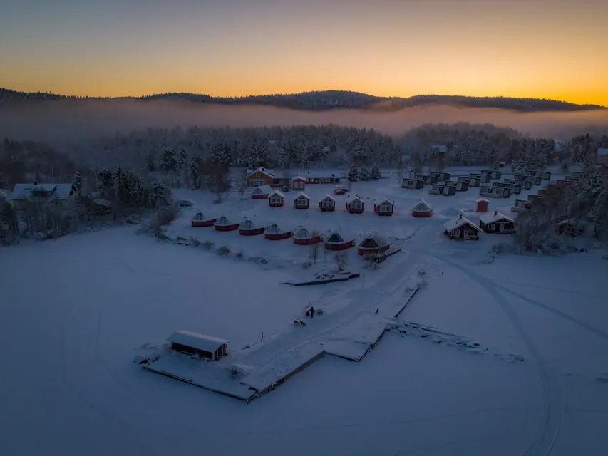 An aerial shot of aurora cabins at the shores of the frozen Lake Inari, Finland