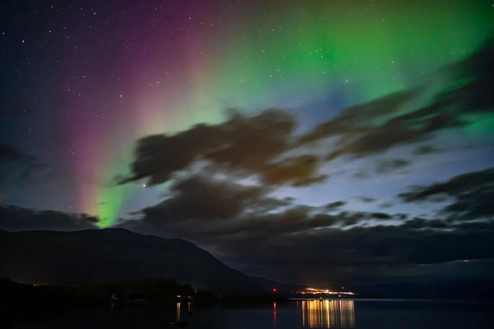 Green and Red Aurora Borealis over Sea and Hills