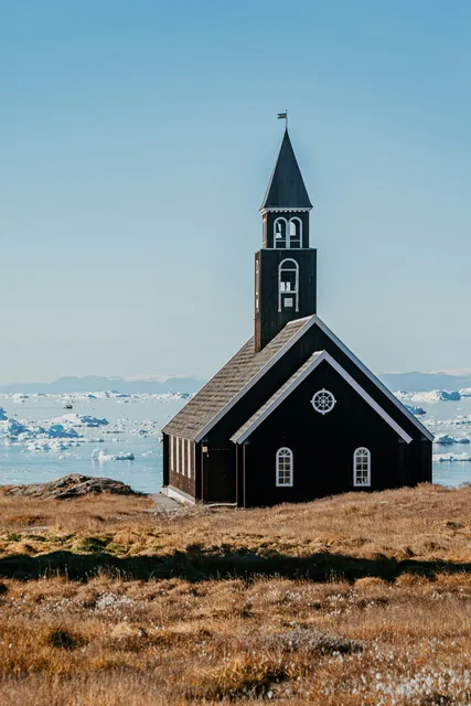 Beautiful black wooden church on the shoreline in Greenland