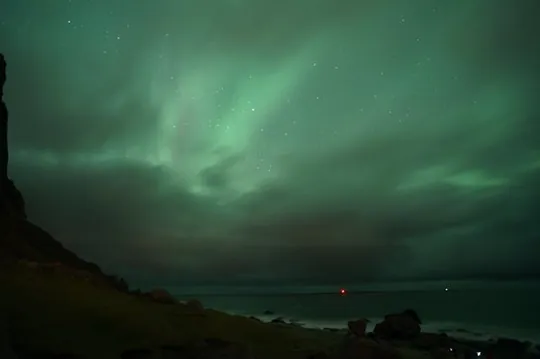 Aurora Borealis in the sky over the sea and mountains on Kvaløya island